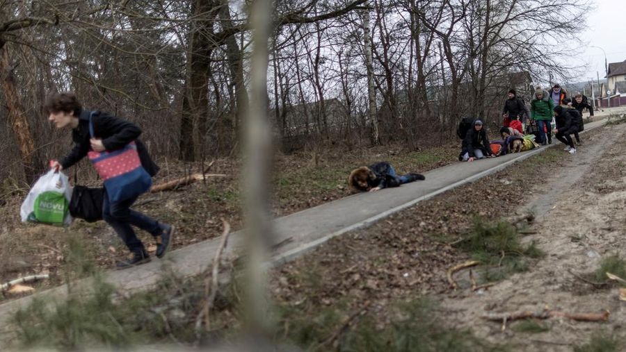 Warga melintasi jalan setapak di bawah jembatan yang hancur saat melarikan diri dari kota Irpin, Ukraina, MInggu (6/3/2022).  Di Irpin, dekat Kyiv, ratusan warga berjalan kaki dan bahkan dengan gerobak dorong melewati sisa-sisa jembatan yang hancur untuk menyeberangi sungai dan meninggalkan kota. (AP Photo/Oleksandr Ratushniak)