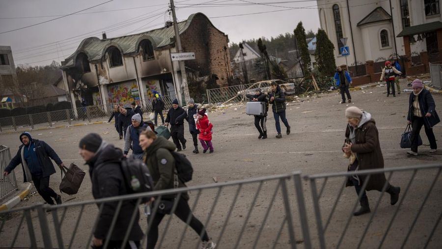 Warga Ukraina melarikan diri saat artileri bergema di dekatnya di Irpin, di pinggiran Kyiv, Ukraina, Senin (7/3/2022). (AP Photo/Emilio Morenatti)