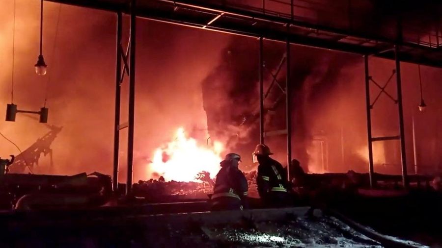Petugas pemadam kebakaran memadamkan api di depot minyak yang menurut Layanan Darurat Negara Ukraina disebabkan oleh serangan Rusia di wilayah Zhytomyr, Ukraina, Senin (7/3/2022). (Tangkapan layar video State Emergency Services of Ukraine/Handout via REUTERS)