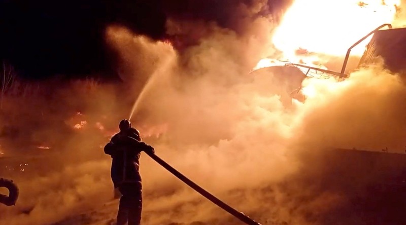 Petugas pemadam kebakaran memadamkan api di depot minyak yang menurut Layanan Darurat Negara Ukraina disebabkan oleh serangan Rusia di wilayah Zhytomyr, Ukraina, Senin (7/3/2022). (Tangkapan layar video State Emergency Services of Ukraine/Handout via REUTERS)