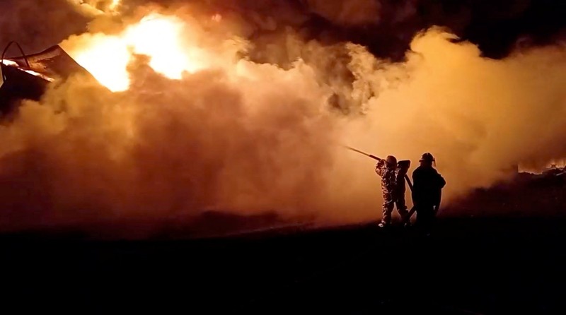 Petugas pemadam kebakaran memadamkan api di depot minyak yang menurut Layanan Darurat Negara Ukraina disebabkan oleh serangan Rusia di wilayah Zhytomyr, Ukraina, Senin (7/3/2022). (Tangkapan layar video State Emergency Services of Ukraine/Handout via REUTERS)