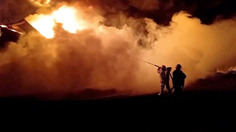 Petugas pemadam kebakaran memadamkan api di depot minyak yang menurut Layanan Darurat Negara Ukraina disebabkan oleh serangan Rusia di wilayah Zhytomyr, Ukraina, Senin (7/3/2022). (Tangkapan layar video State Emergency Services of Ukraine/Handout via REUTERS)