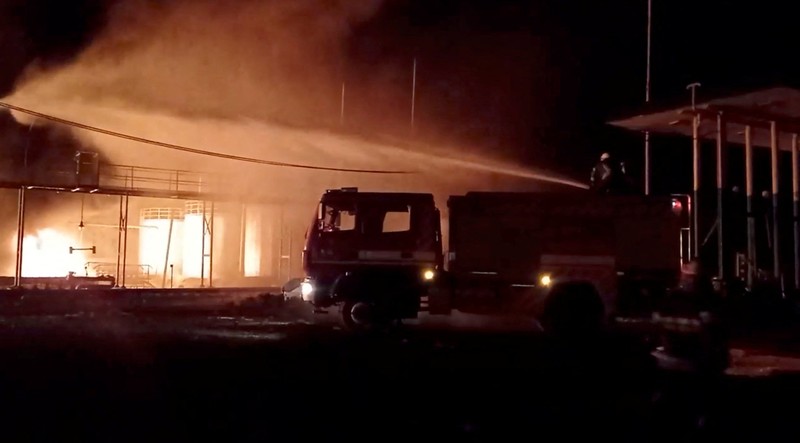 Petugas pemadam kebakaran memadamkan api di depot minyak yang menurut Layanan Darurat Negara Ukraina disebabkan oleh serangan Rusia di wilayah Zhytomyr, Ukraina, Senin (7/3/2022). (Tangkapan layar video State Emergency Services of Ukraine/Handout via REUTERS)