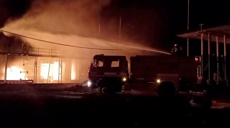 Petugas pemadam kebakaran memadamkan api di depot minyak yang menurut Layanan Darurat Negara Ukraina disebabkan oleh serangan Rusia di wilayah Zhytomyr, Ukraina, Senin (7/3/2022). (Tangkapan layar video State Emergency Services of Ukraine/Handout via REUTERS)