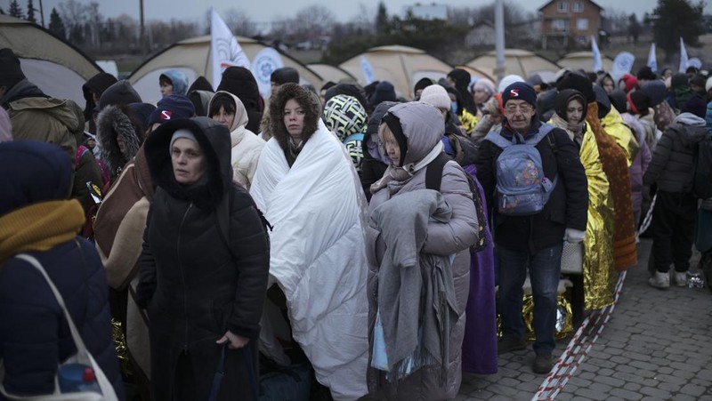 Relawan membagikan makanan kepada orang-orang yang melintasi perbatasan dari Ukraina ke Polandia, setelah melarikan diri dari iserangan Rusia ke Ukraina, di pos pemeriksaan perbatasan di Medyka, Polandia, Selasa (8/3/2022). (REUTERS/Fabrizio Bensch)