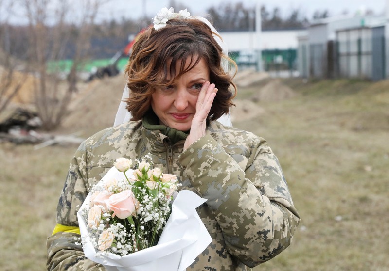 Pernikahan Militer Ukraina Anggota Pasukan Pertahanan Teritorial Ukraina Lesia Ivashchenko dan Valerii Fylymonov mendengarkan seorang pendeta di pernikahan mereka selama konflik Ukraina-Rusia, di sebuah pos pemeriksaan di Kyiv, Ukraina, Minggu (6/3/2022). (REUTERS/Mykola Tymchenko)