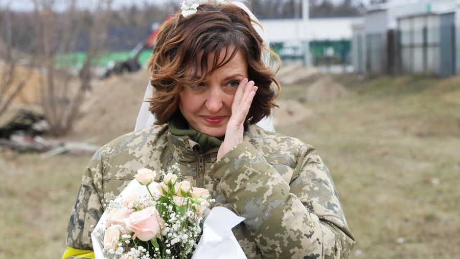 Anggota Pasukan Pertahanan Teritorial Ukraina Lesia Ivashchenko dan Valerii Fylymonov mendengarkan seorang pendeta di pernikahan mereka selama konflik Ukraina-Rusia, di sebuah pos pemeriksaan di Kyiv, Ukraina, Minggu (6/3/2022). (REUTERS/Mykola Tymchenko)