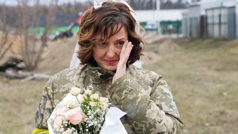 Anggota Pasukan Pertahanan Teritorial Ukraina Lesia Ivashchenko dan Valerii Fylymonov mendengarkan seorang pendeta di pernikahan mereka selama konflik Ukraina-Rusia, di sebuah pos pemeriksaan di Kyiv, Ukraina, Minggu (6/3/2022). (REUTERS/Mykola Tymchenko)