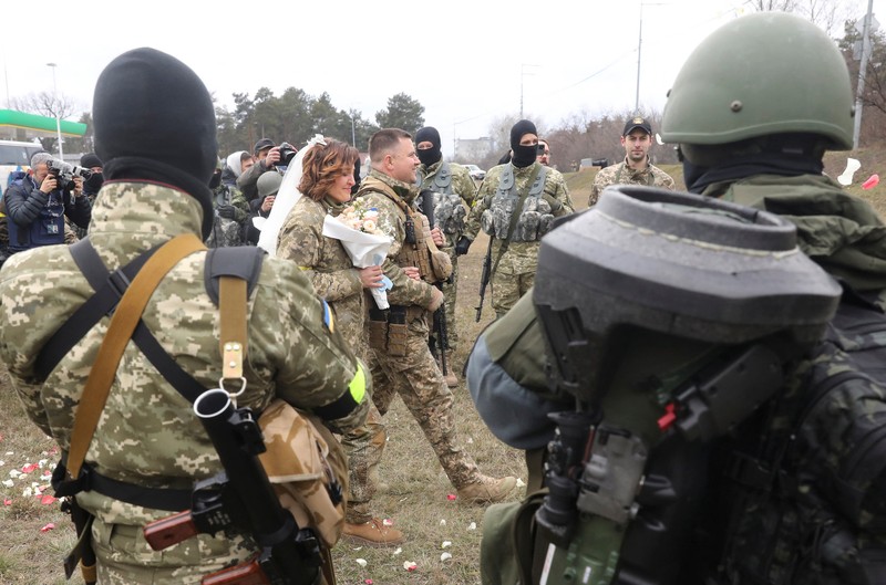 Pernikahan Militer Ukraina Anggota Pasukan Pertahanan Teritorial Ukraina Lesia Ivashchenko dan Valerii Fylymonov mendengarkan seorang pendeta di pernikahan mereka selama konflik Ukraina-Rusia, di sebuah pos pemeriksaan di Kyiv, Ukraina, Minggu (6/3/2022). (REUTERS/Mykola Tymchenko)