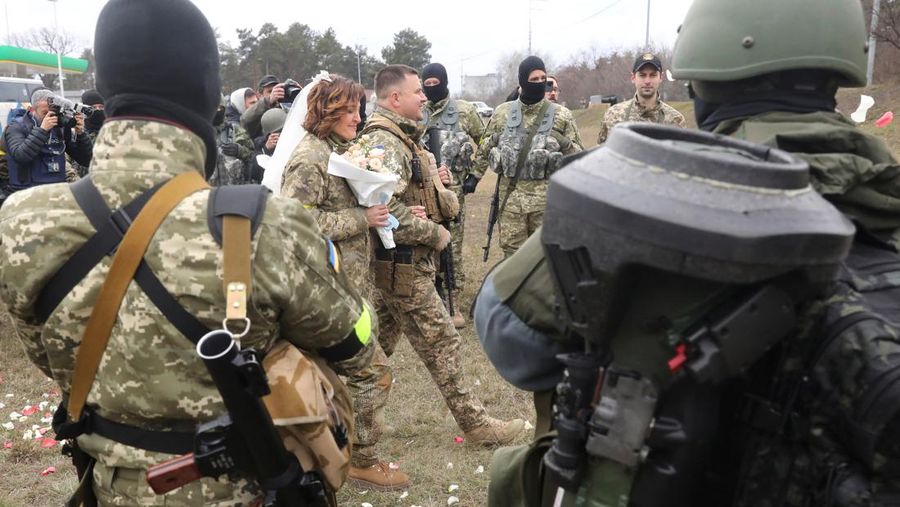 Anggota Pasukan Pertahanan Teritorial Ukraina Lesia Ivashchenko dan Valerii Fylymonov mendengarkan seorang pendeta di pernikahan mereka selama konflik Ukraina-Rusia, di sebuah pos pemeriksaan di Kyiv, Ukraina, Minggu (6/3/2022). (REUTERS/Mykola Tymchenko)