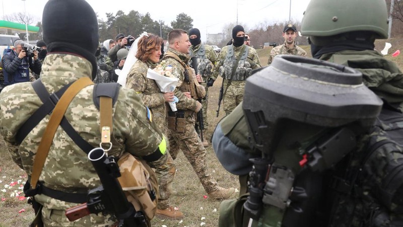 Anggota Pasukan Pertahanan Teritorial Ukraina Lesia Ivashchenko dan Valerii Fylymonov mendengarkan seorang pendeta di pernikahan mereka selama konflik Ukraina-Rusia, di sebuah pos pemeriksaan di Kyiv, Ukraina, Minggu (6/3/2022). (REUTERS/Mykola Tymchenko)
