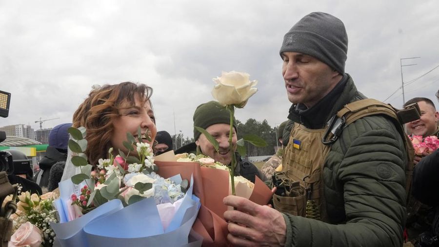 Mantan juara dunia tinju kelas berat Ukraina Wladimir Klitschko (kanan) mengucapkan selamat kepada anggota Pasukan Pertahanan Teritorial Ukraina Lesia Ivashchenko (kiri) dan Valerii Fylymonov yang baru menikah, setelah upacara pernikahan di sebuah pos pemeriksaan di Kyiv, Ukraina, Minggu (6/3/2022). (AP Photo/Efrem Lukatsky)