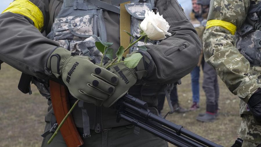 Anggota Pasukan Pertahanan Teritorial Ukraina Lesia Ivashchenko dan Valerii Fylymonov mendengarkan seorang pendeta di pernikahan mereka selama konflik Ukraina-Rusia, di sebuah pos pemeriksaan di Kyiv, Ukraina, Minggu (6/3/2022). (REUTERS/Mykola Tymchenko)