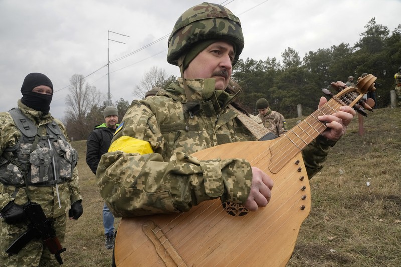 Pernikahan Militer Ukraina Anggota Pasukan Pertahanan Teritorial Ukraina Lesia Ivashchenko dan Valerii Fylymonov mendengarkan seorang pendeta di pernikahan mereka selama konflik Ukraina-Rusia, di sebuah pos pemeriksaan di Kyiv, Ukraina, Minggu (6/3/2022). (REUTERS/Mykola Tymchenko)
