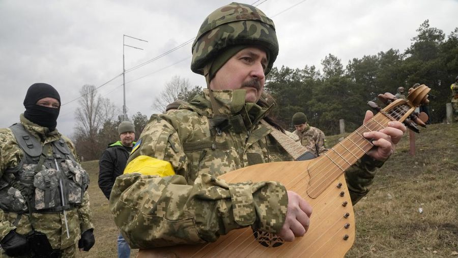 Anggota Pasukan Pertahanan Teritorial Ukraina Lesia Ivashchenko dan Valerii Fylymonov mendengarkan seorang pendeta di pernikahan mereka selama konflik Ukraina-Rusia, di sebuah pos pemeriksaan di Kyiv, Ukraina, Minggu (6/3/2022). (REUTERS/Mykola Tymchenko)