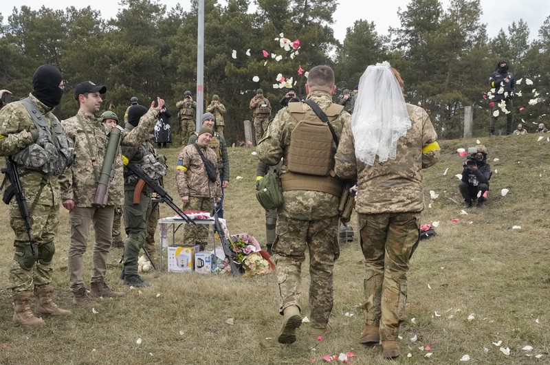 Anggota Pasukan Pertahanan Teritorial Ukraina Lesia Ivashchenko dan Valerii Fylymonov mendengarkan seorang pendeta di pernikahan mereka selama konflik Ukraina-Rusia, di sebuah pos pemeriksaan di Kyiv, Ukraina, Minggu (6/3/2022). (REUTERS/Mykola Tymchenko)