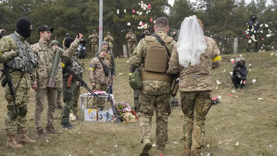 Anggota Pasukan Pertahanan Teritorial Ukraina Lesia Ivashchenko dan Valerii Fylymonov mendengarkan seorang pendeta di pernikahan mereka selama konflik Ukraina-Rusia, di sebuah pos pemeriksaan di Kyiv, Ukraina, Minggu (6/3/2022). (REUTERS/Mykola Tymchenko)