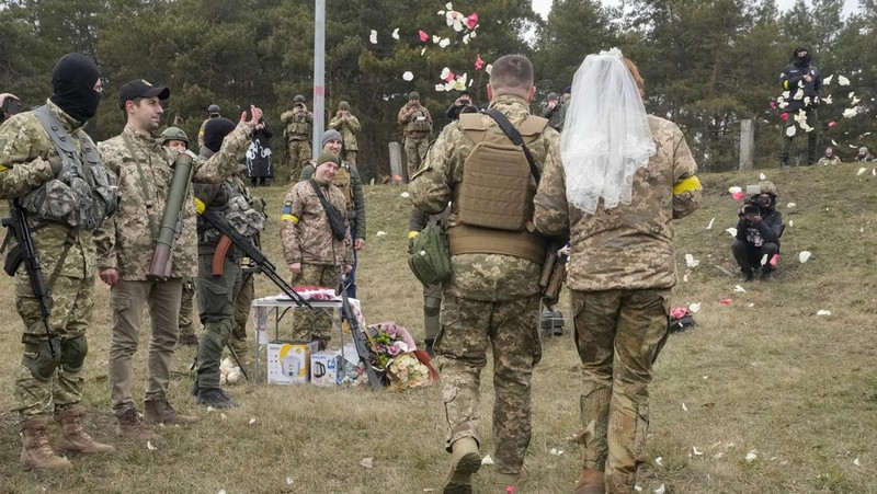 Anggota Pasukan Pertahanan Teritorial Ukraina Lesia Ivashchenko dan Valerii Fylymonov mendengarkan seorang pendeta di pernikahan mereka selama konflik Ukraina-Rusia, di sebuah pos pemeriksaan di Kyiv, Ukraina, Minggu (6/3/2022). (REUTERS/Mykola Tymchenko)