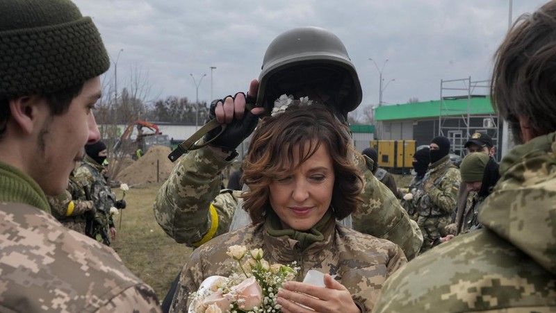 Anggota Pasukan Pertahanan Teritorial Ukraina Lesia Ivashchenko dan Valerii Fylymonov mendengarkan seorang pendeta di pernikahan mereka selama konflik Ukraina-Rusia, di sebuah pos pemeriksaan di Kyiv, Ukraina, Minggu (6/3/2022). (REUTERS/Mykola Tymchenko)