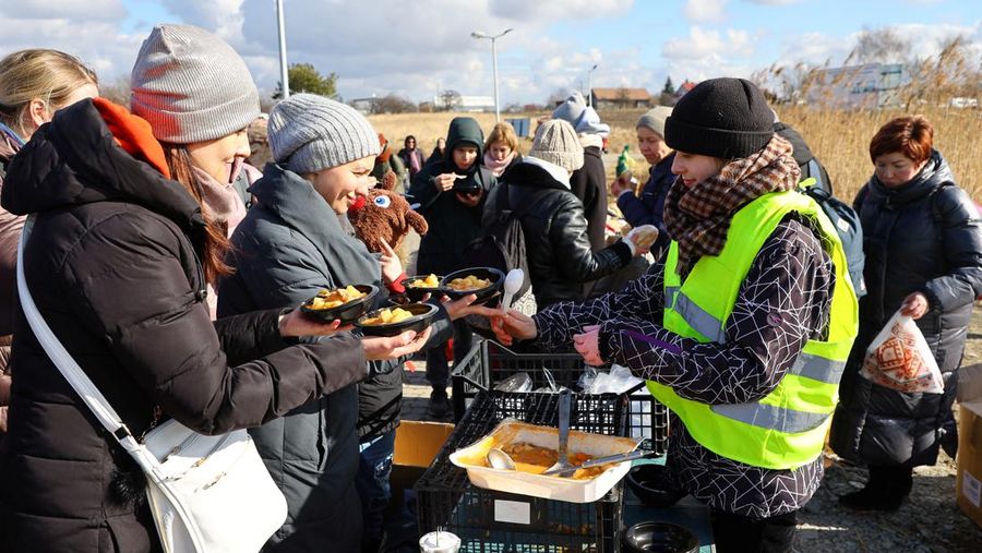 Relawan membagikan makanan kepada orang-orang yang melintasi perbatasan dari Ukraina ke Polandia, setelah melarikan diri dari iserangan Rusia ke Ukraina, di pos pemeriksaan perbatasan di Medyka, Polandia, Selasa (8/3/2022). (REUTERS/Fabrizio Bensch)