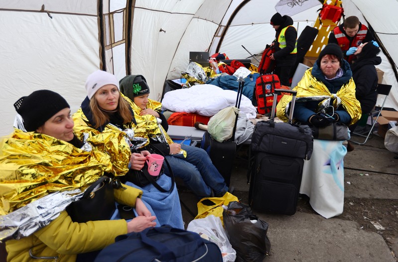 Relawan Membagikan Makanan Kepada Pengung warga Ukraina di Polandia Relawan membagikan makanan kepada orang-orang yang melintasi perbatasan dari Ukraina ke Polandia, setelah melarikan diri dari iserangan Rusia ke Ukraina, di pos pemeriksaan perbatasan di Medyka, Polandia, Selasa (8/3/2022). (REUTERS/Fabrizio Bensch)