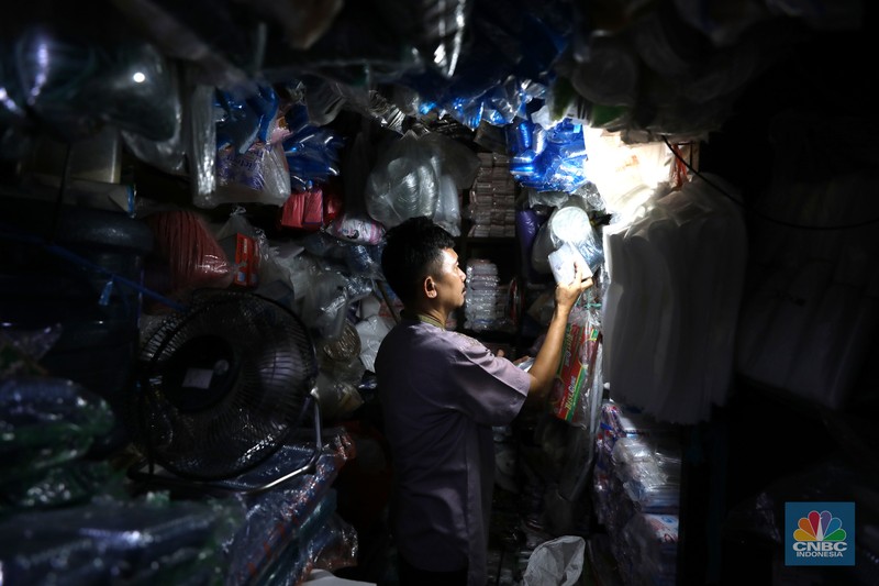 Pedagang melayani pembeli kantong plastik di Pasar Jaya Slipi, Jakarta, Rabu (9/3/2022). Lonjakan harga minyak mentah mendongkrak kenaikan harga bahan baku plastik. Baik untuk jenis Low Density Polyethylene (LDPE), Linear Low Density Polyethylene (LLDPE), High Density Polyethylene (HDPE), maupun Polypropylene (PP). (CNBC Indonesia/ Tri Susilo)