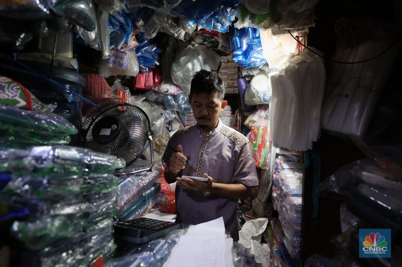 Pedagang melayani pembeli kantong plastik di Pasar Jaya Slipi, Jakarta, Rabu (9/3/2022). Lonjakan harga minyak mentah mendongkrak kenaikan harga bahan baku plastik. Baik untuk jenis Low Density Polyethylene (LDPE), Linear Low Density Polyethylene (LLDPE), High Density Polyethylene (HDPE), maupun Polypropylene (PP). (CNBC Indonesia/ Tri Susilo)