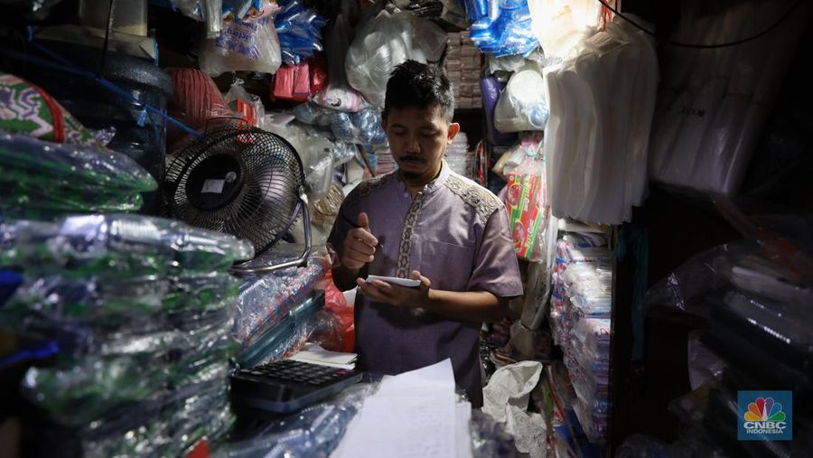 Pedagang melayani pembeli kantong plastik di Pasar Jaya Slipi, Jakarta, Rabu (9/3/2022). Lonjakan harga minyak mentah mendongkrak kenaikan harga bahan baku plastik. Baik untuk jenis Low Density Polyethylene (LDPE), Linear Low Density Polyethylene (LLDPE), High Density Polyethylene (HDPE), maupun Polypropylene (PP). (CNBC Indonesia/ Tri Susilo)