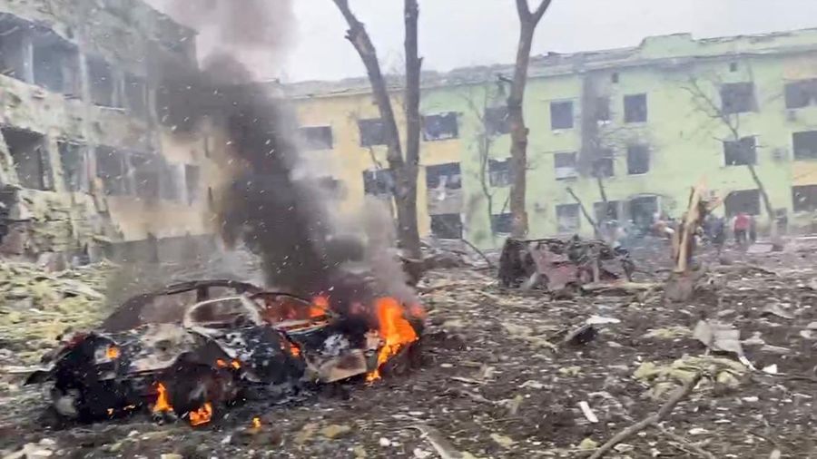 Sebuah mobil terbakar setelah rumah sakit anak-anak rusak saat serangan Rusia di Mariupol, Ukraina, Rabu (9/3/2022). (Tangkapan Layar video Ukraine Military/Handout via REUTERS)