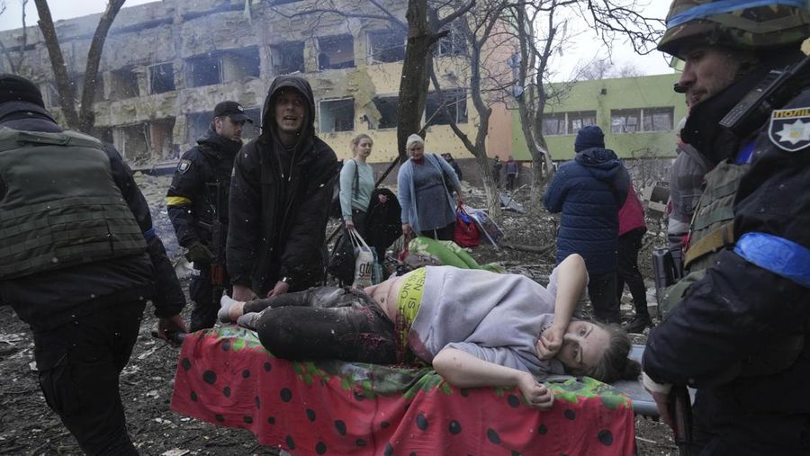 Pekerja darurat Ukraina dan sukarelawan membawa seorang wanita hamil yang terluka dari rumah sakit bersalin yang rusak akibat penembakan di Mariupol, Ukraina, Rabu (9/3/2022). Serangan Rusia telah merusak parah sebuah rumah sakit bersalin di kota pelabuhan Mariupol yang terkepung, kata pejabat Ukraina. (AP Photo/Evgeniy Maloletka)
