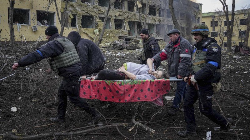 Ukrainian emergency employees and volunteers carry an injured pregnant woman from the damaged by shelling maternity hospital in Mariupol, Ukraine, Wednesday, March 9, 2022. A Russian attack has severely damaged a maternity hospital in the besieged port city of Mariupol, Ukrainian officials say. (AP Photo/Evgeniy Maloletka)