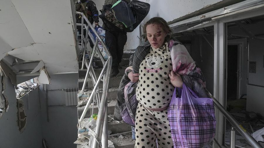 Ukrainian emergency employees and volunteers carry an injured pregnant woman from the damaged by shelling maternity hospital in Mariupol, Ukraine, Wednesday, March 9, 2022. A Russian attack has severely damaged a maternity hospital in the besieged port city of Mariupol, Ukrainian officials say. (AP Photo/Evgeniy Maloletka)