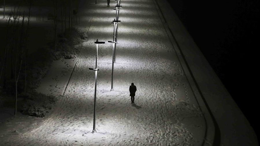 Pedestrians walk along a snow-covered promenade during a snowfall in Istanbul, Turkey, Saturday, March 12, 2022. (AP Photo/Emrah Gurel)