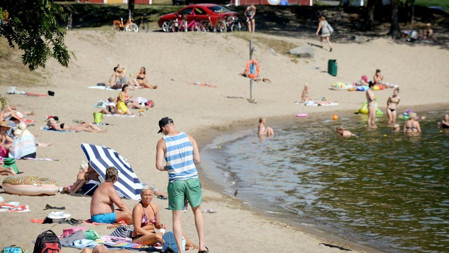Sunbathers enjoy the hot weather as they sit on a beach in Vaasa, Finland, Thursday, July 19, 2018. (Mikko Stig/Lehtikuva via AP)