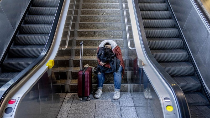 Travelers stand in front of a display board in an airport terminal in Hamburg, Germany, in the morning of Tuesday, March 22, 2022. Due to a warning strike by the trade union ver.di, the security checkpoint remains closed all day and no departures take place. (Daniel Bockwoldt/dpa via AP)