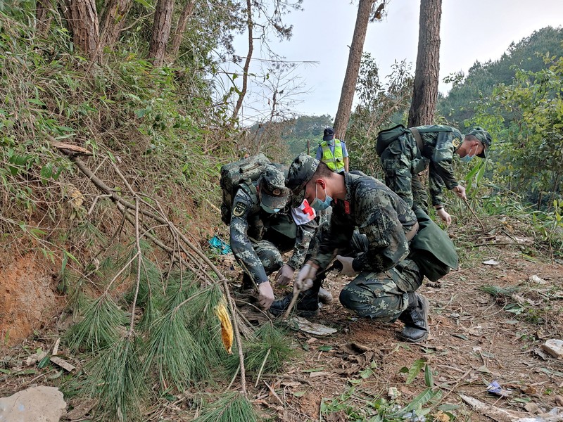 CHINA-CRASH/ A police officer carries a traffic cone after police vehicles enter Lu village near the site where a China Eastern Airlines Boeing 737-800 plane flying from Kunming to Guangzhou crashed, in Wuzhou, Guangxi Zhuang Autonomous Region, China March 22, 2022. REUTERS/Carlos Garcia Rawlins
