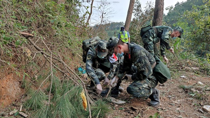 A police officer carries a traffic cone after police vehicles enter Lu village near the site where a China Eastern Airlines Boeing 737-800 plane flying from Kunming to Guangzhou crashed, in Wuzhou, Guangxi Zhuang Autonomous Region, China March 22, 2022. REUTERS/Carlos Garcia Rawlins