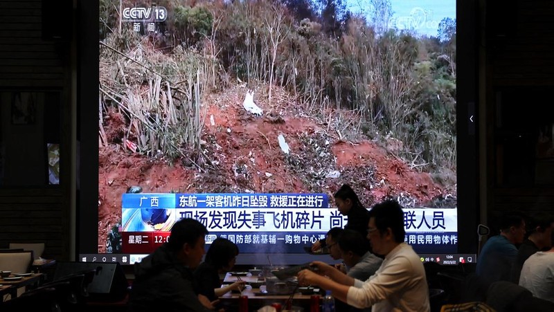 A screen shows news footage of plane debris at the site where a China Eastern Airlines Boeing 737-800 plane flying from Kunming to Guangzhou crashed in Wuzhou of Guangxi Zhuang Autonomous Region, while customers dine at a restaurant in Beijing, China March 22, 2022. REUTERS/Tingshu Wang