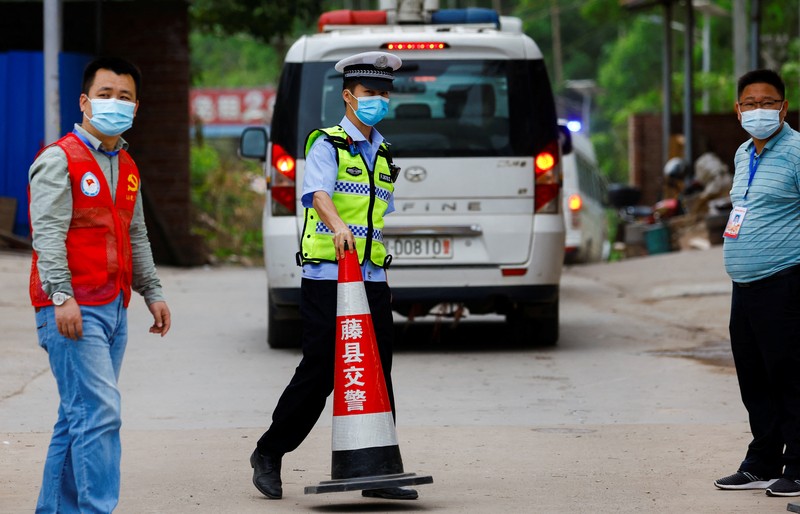 CHINA-CRASH/ A police officer carries a traffic cone after police vehicles enter Lu village near the site where a China Eastern Airlines Boeing 737-800 plane flying from Kunming to Guangzhou crashed, in Wuzhou, Guangxi Zhuang Autonomous Region, China March 22, 2022. REUTERS/Carlos Garcia Rawlins