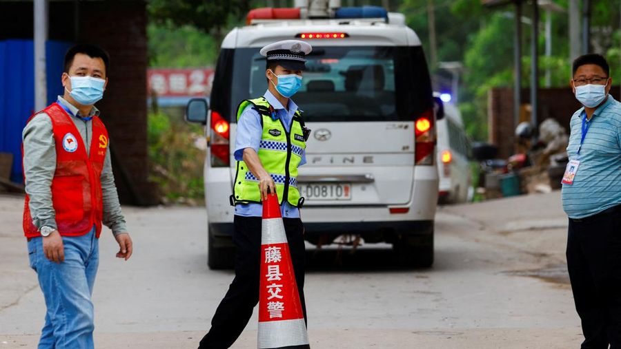 A police officer carries a traffic cone after police vehicles enter Lu village near the site where a China Eastern Airlines Boeing 737-800 plane flying from Kunming to Guangzhou crashed, in Wuzhou, Guangxi Zhuang Autonomous Region, China March 22, 2022. REUTERS/Carlos Garcia Rawlins