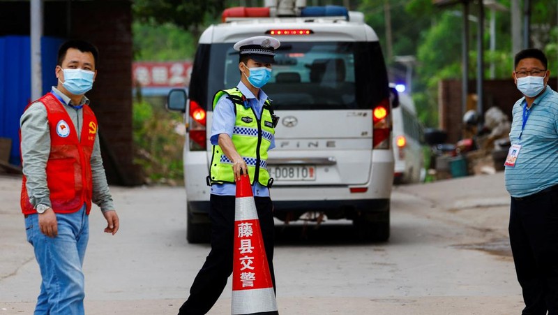 A police officer carries a traffic cone after police vehicles enter Lu village near the site where a China Eastern Airlines Boeing 737-800 plane flying from Kunming to Guangzhou crashed, in Wuzhou, Guangxi Zhuang Autonomous Region, China March 22, 2022. REUTERS/Carlos Garcia Rawlins