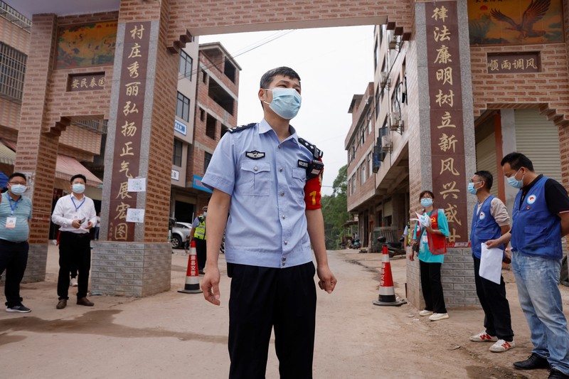 CHINA-CRASH/ A police officer carries a traffic cone after police vehicles enter Lu village near the site where a China Eastern Airlines Boeing 737-800 plane flying from Kunming to Guangzhou crashed, in Wuzhou, Guangxi Zhuang Autonomous Region, China March 22, 2022. REUTERS/Carlos Garcia Rawlins