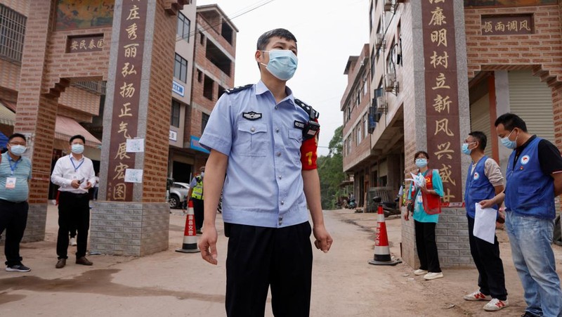 A police officer carries a traffic cone after police vehicles enter Lu village near the site where a China Eastern Airlines Boeing 737-800 plane flying from Kunming to Guangzhou crashed, in Wuzhou, Guangxi Zhuang Autonomous Region, China March 22, 2022. REUTERS/Carlos Garcia Rawlins