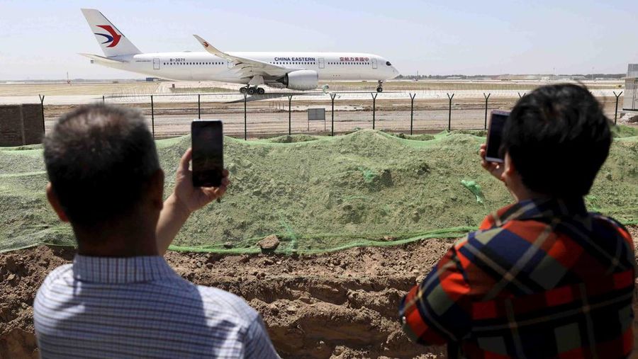 FILE - Residents watch as a China Eastern passenger jet prepares to take off on a test flight from the new Beijing Daxing International Airport on Monday, May 13, 2019. State media are reporting a Chinese airliner from China Eastern with 133 people on board crashed in the southern province of Guangxi on Monday, sparking a mountainside fire. (AP Photo/Ng Han Guan, File)