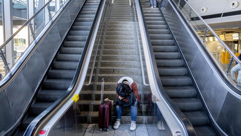 Travelers stand in front of a display board in an airport terminal in Hamburg, Germany, in the morning of Tuesday, March 22, 2022. Due to a warning strike by the trade union ver.di, the security checkpoint remains closed all day and no departures take place. (Daniel Bockwoldt/dpa via AP)