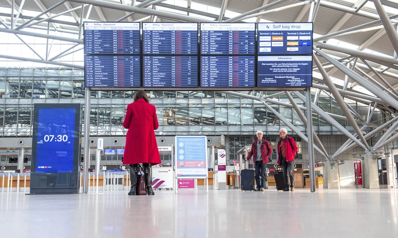 Germany Airport Strike Travelers stand in front of a display board in an airport terminal in Hamburg, Germany, in the morning of Tuesday, March 22, 2022. Due to a warning strike by the trade union ver.di, the security checkpoint remains closed all day and no departures take place. (Daniel Bockwoldt/dpa via AP)