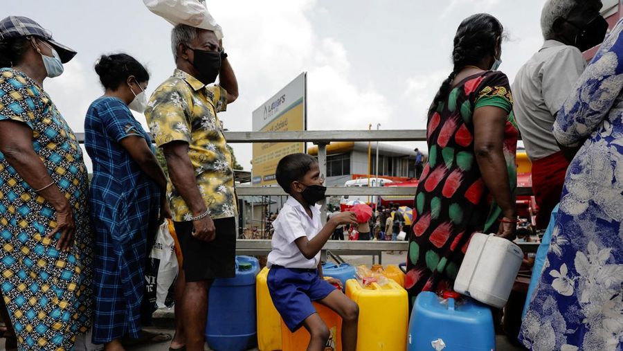 A boy sits on empty containers with his parents as they wait to buy kerosene oil used for kerosene cookers amid a shortage of domestic gas due to country's economic crisis, at a fuel station in Colombo, Sri Lanka March 21, 2022. REUTERS/Dinuka Liyanawatte
