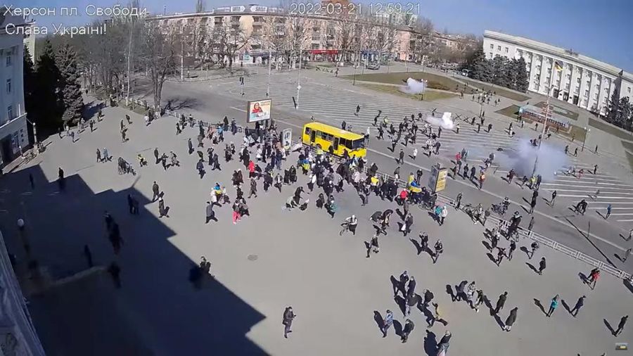 CCTV footage appears to show Russian troops (top, near building) firing stun grenades into a crowd of protesters, some with Ukrainian flags, amid the Russian invasion, along Ushakova Avenue in Kherson, Ukraine March 21, 2022 in this still image from video obtained by REUTERS THIS IMAGE HAS BEEN SUPPLIED BY A THIRD PARTY. NO RESALES. NO ARCHIVES