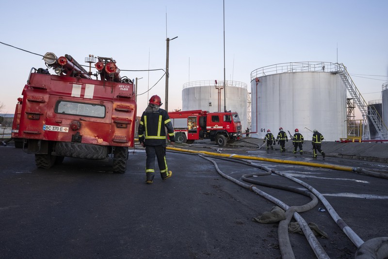 Petugas pemadam kebakaran bekerja di lokasi setelah serangan udara roket Rusia yang menghantam fasilitas minyak di kawasan industri di pinggiran timur laut Lviv, Ukraina, Minggu, (27/3/2022). (AP Photo/Nariman El-Mofty)