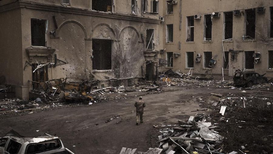 Seorang prajurit Ukraina berjalan di luar gedung administrasi regional, yang rusak berat setelah serangan Rusia awal bulan ini di Kharkiv, Ukraina, Minggu (27/3/2022). (AP Photo/Felipe Dana)